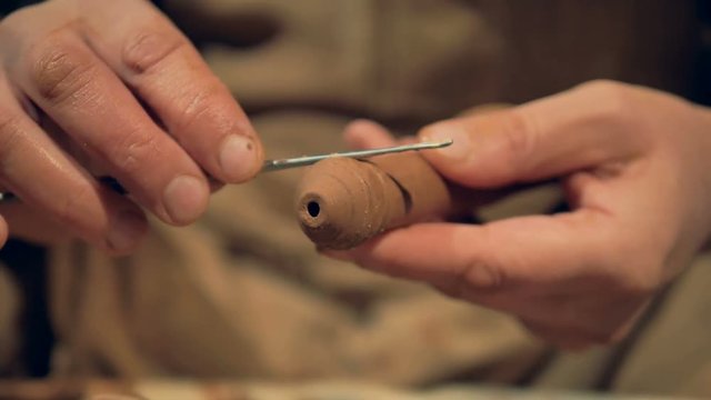A cleaning tool in potters hands finishes a clay handle.  