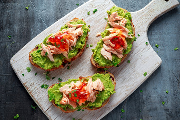 Homemade Toast sandwich with Salmon, Avocado and chilli jam on wihte wooden board. healthy food
