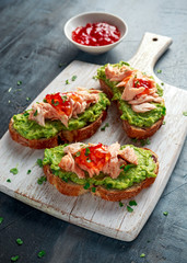 Homemade Toast sandwich with Salmon, Avocado and chilli jam on wihte wooden board. healthy food