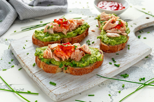Homemade Toast sandwich with Salmon, Avocado and chilli jam on wihte wooden board. healthy food