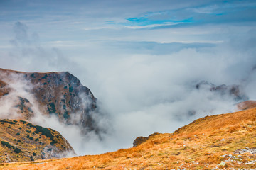 foggy mountain landscape with clouds above the peaks