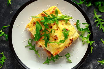 Homemade lasagna with minced beef bolognese and bechamel sauce topped wild arugula, parmesan cheese