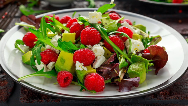 Fresh Tasty Raspberry salad with avocado, green vegetables, nuts, feta cheese, olive oil and herbs. healthy food.