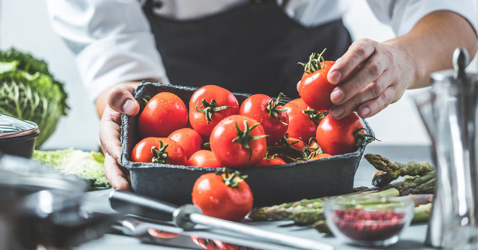 Chefkoch in der K&uuml;che mit Frischem Gem&uuml;se(Tomaten)