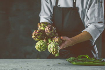 Chefkoch in der Küche mit Frischem Gemüse(Artischocken)