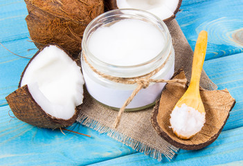 Coconut oil and fresh coconuts on a wooden table.