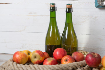two bottles of cider and red apples