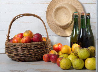 three bottles of cider and basket of apples