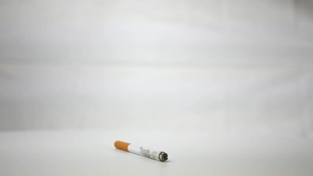 Ugly decaying cigarette spinning over white