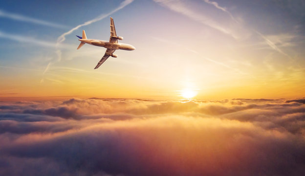 Commercial airplane jetliner flying above clouds in beautiful sunset light.