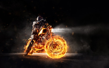 Dark motorbiker staying on burning motorcycle, separated on black background. © Jag_cz