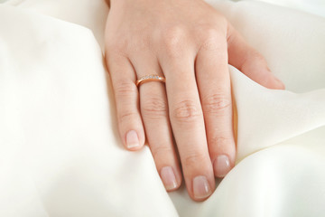 Woman's hand with luxury engagement ring on fabric, closeup