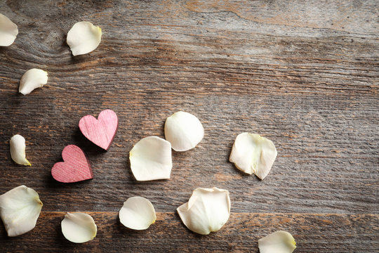 Composition with pink hearts and rose petals on wooden background, top view