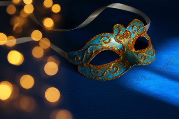 Image of elegant blue and gold venetian, mardi gras mask over blue background.