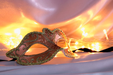 Image of elegant venetian mask over gold silk background.