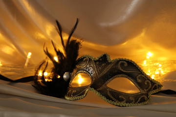 Image of elegant venetian mask over gold silk background. © tomertu