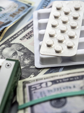 Dollar bills along with white pill package, conceptual image co-payment health