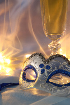 Image of elegant venetian mask and glasses of champagne over silk background.