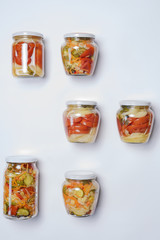 Fototapeta na wymiar Vegetable home-made preserves of cucumbers, tomatoes, cauliflower, carrots, onions with spices in beautiful jars located on a slick background