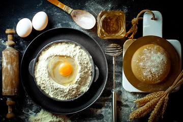 Dough with flour on an old background in a composition with kitchen accessories