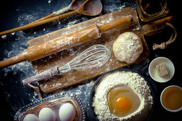 Dough with flour on an old background in a composition with kitchen accessories