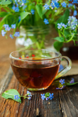 Cup of tea with lilac flowers on marble background