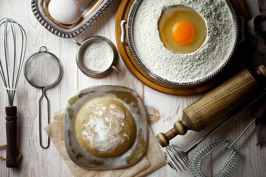 Dough with flour on an old background in a composition with kitchen accessories