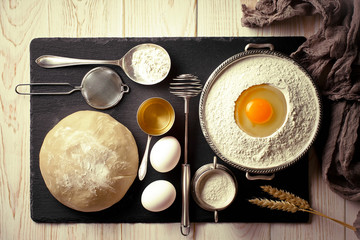 Dough with flour on an old background in a composition with kitchen accessories