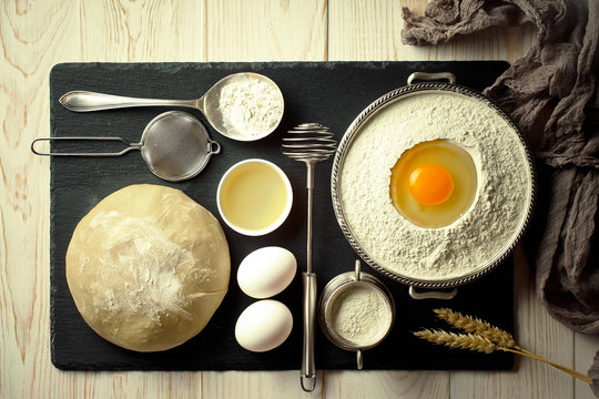 Dough with flour on an old background in a composition with kitchen accessories