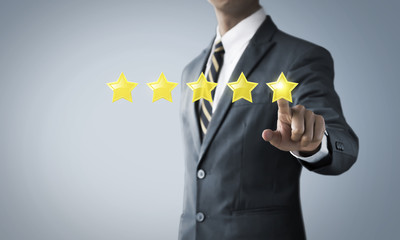 Increase rating, ranking, review, evaluation or classification concept. Businessman is pointing on five stars rating on bright tone background.