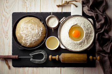 Dough with flour on an old background in a composition with kitchen accessories