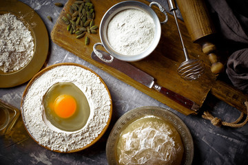 Dough with flour on an old background in a composition with kitchen accessories