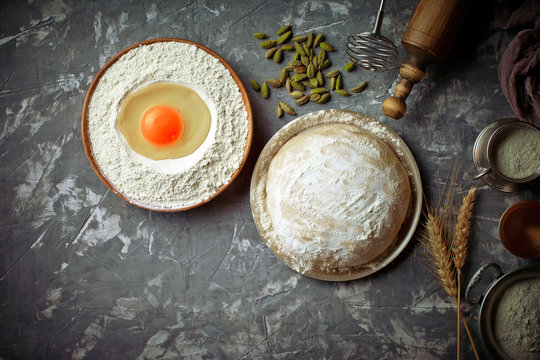Dough with flour on an old background in a composition with kitchen accessories