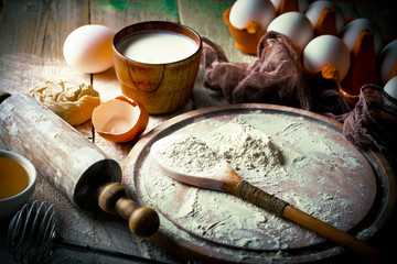 Dough with flour on an old background in a composition with kitchen accessories