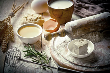 Dough with flour on an old background in a composition with kitchen accessories
