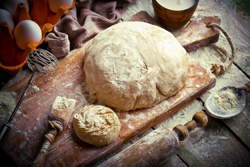 Fototapeta premium Dough with flour on an old background in a composition with kitchen accessories