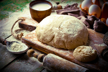 Fototapeta premium Dough with flour on an old background in a composition with kitchen accessories
