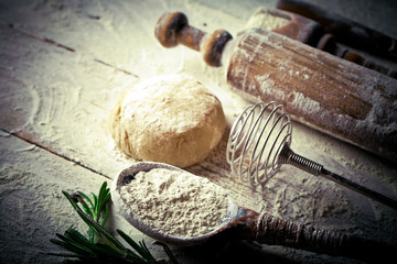 Dough with flour on an old background in a composition with kitchen accessories