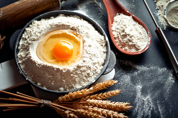 Dough with flour on an old background in a composition with kitchen accessories