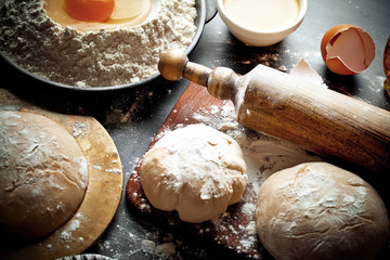 Dough with flour on an old background in a composition with kitchen accessories