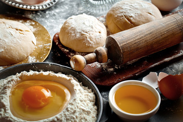 Dough with flour on an old background in a composition with kitchen accessories