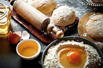 Dough with flour on an old background in a composition with kitchen accessories