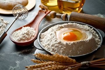 Dough with flour on an old background in a composition with kitchen accessories