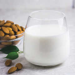 Glass of almond milk and almonds on white marble background. Selective focus, space for text, toned.