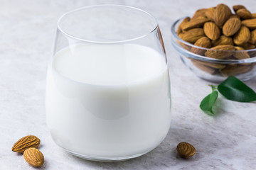 Healthy homemade vegan nut milk and almonds on white marble background. Selective focus, space for text.