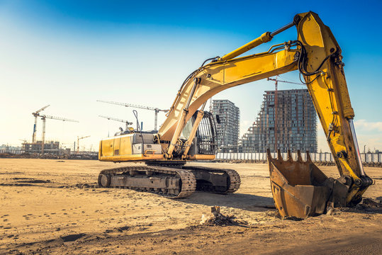 Excavator on construction site with bulldings in background,selective focus