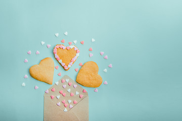 Open craft paper envelope with fly out sugar candies and heart shaped homemade cookies on light blue background. Valentine day. love concept. Gift, message for lover. Space for text.