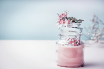 Jar with floral herbal cream with organic herbs and flowers, front view. Natural organic cosmetics. Pastel color. Beauty concept