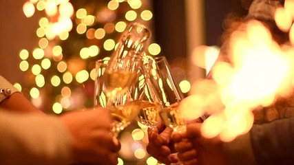 Toasting champagne. Group of people celebrating Christmas party with champagne. Glasses with sparkling wine over glowing background. Slow Motion 4K UHD video footage. 3840X2160