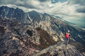 Fototapeta na wymiar A hiker is standing on the edge of the precipice in the Tatra Mountains, Slovakia. Outdoor extreme activity. Unforgettable magnificent panoramic view. Serenity of wild virgin nature.